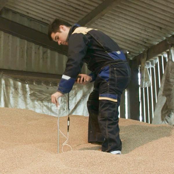 man takes grain temperature readings in a grain store with a Martin Lishman Mini Temp